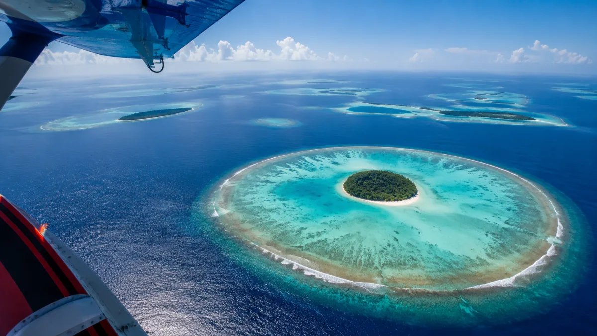 Hidroavión seaplane sobrevolando la laguna turquesa de Maldivas en dirección a un resort de atolón remoto